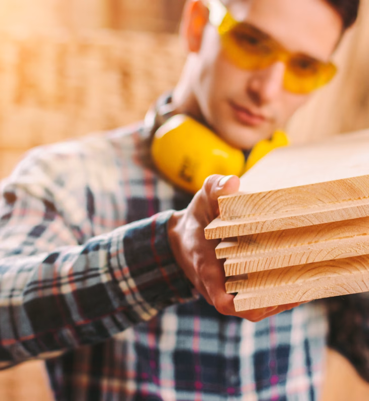 construction worker with goggles looing at boards he is holding
