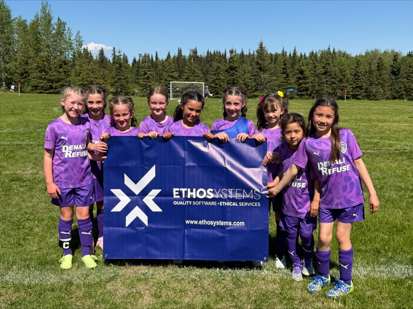 Youth soccer team standing in front of logo