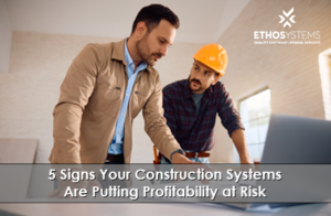 Construction project manager and superintendent reviewing job costs on a laptop to prevent profitability risk
