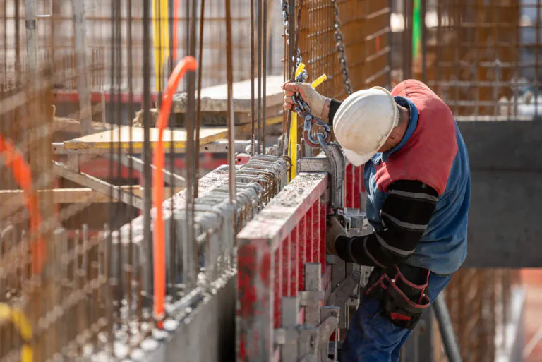 Construction worker in a harness attaching large hook