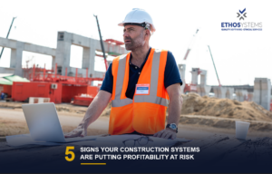 Construction project manager and superintendent reviewing job costs on a laptop to prevent profitability risk