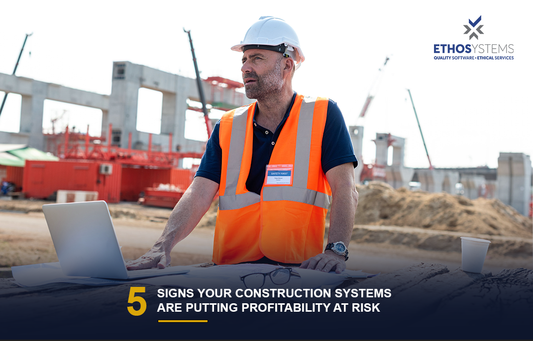 Construction project manager and superintendent reviewing job costs on a laptop to prevent profitability risk