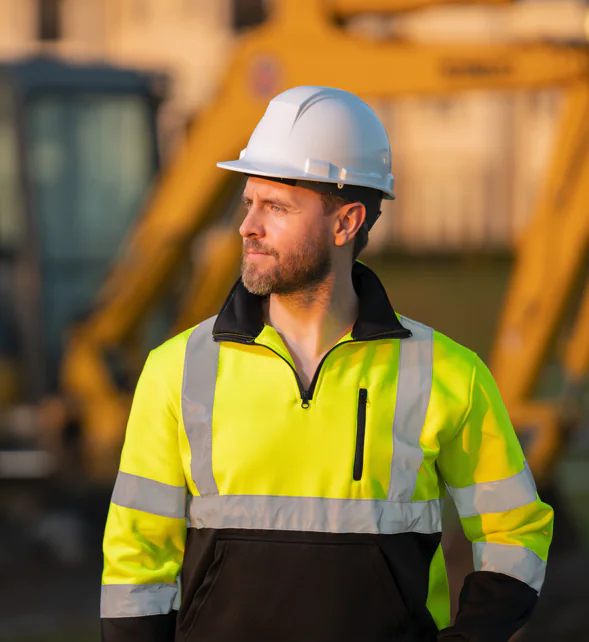 Construction worker standing infront of large equiptment