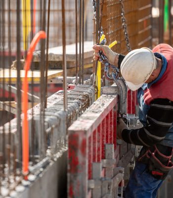 Construction worker in a harness attaching large hook