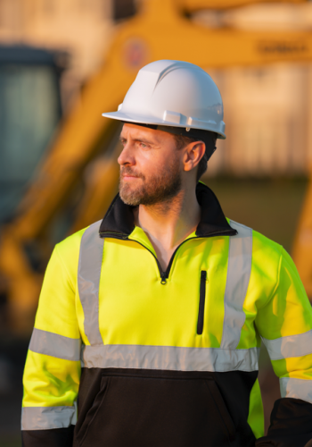Construction worker standing infront of large equiptment