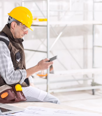 construction worker sitting on desk corner at job site looking at phone