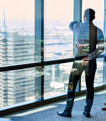 silhouette two office workers pointing and looking out window at buildings