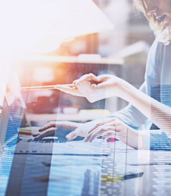 office workers at desk on laptop with building image overlay superimposed